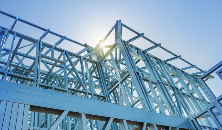 New home under construction using steel frames against a sunny sky.